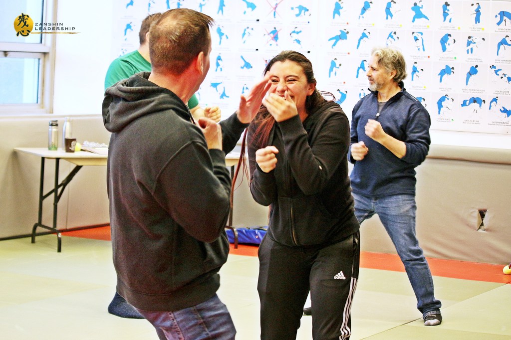 Participants practicing controlled movements in a martial arts session, learning the application of "Zanshin" (awareness) in daily decision-making