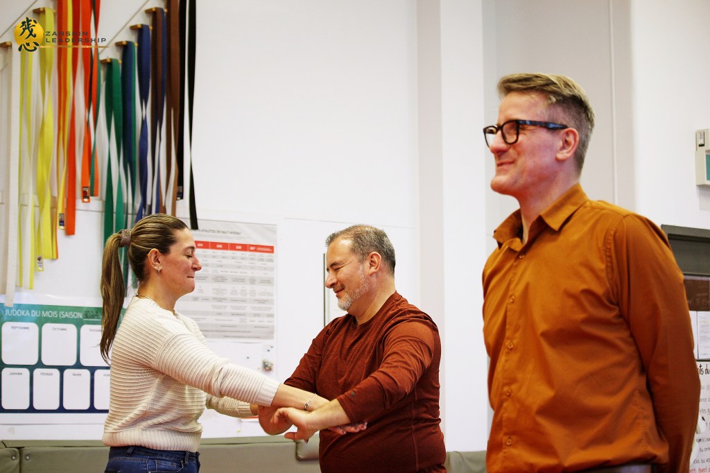 Professionals exploring the concept of "Kuzushi" (breaking balance) through dynamic hands-on martial arts exercises led by Matthaeus Bauernberger