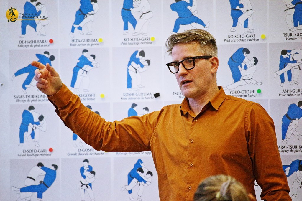 A workshop setting where Matthaeus Bauernberger helps attendees find work-life balance through martial arts-based mindfulness strategies.