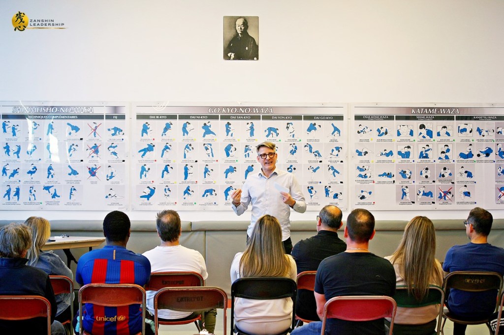 Participants observant des schémas de mouvements martiaux affichés au mur.